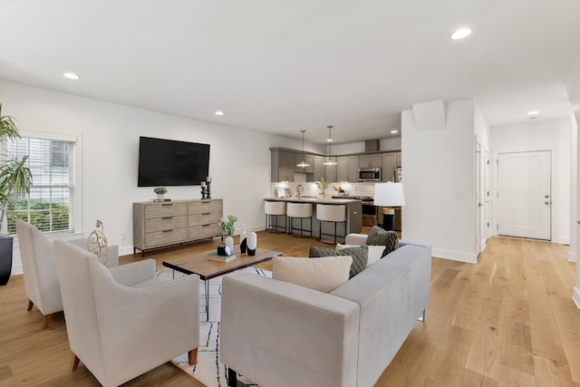 living room with light hardwood / wood-style floors and sink