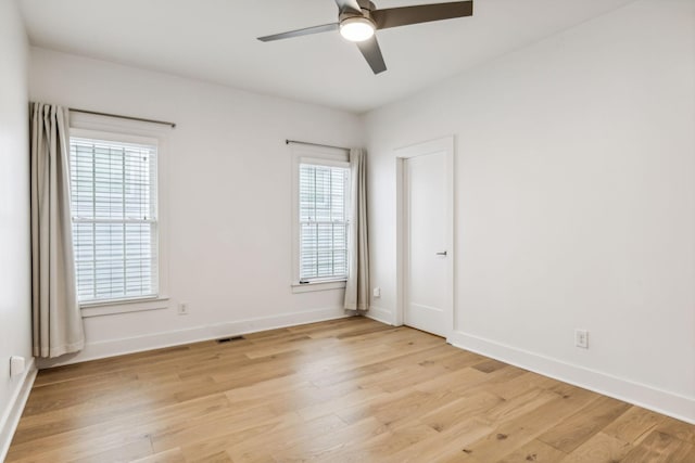 spare room featuring ceiling fan, light wood-type flooring, and a wealth of natural light