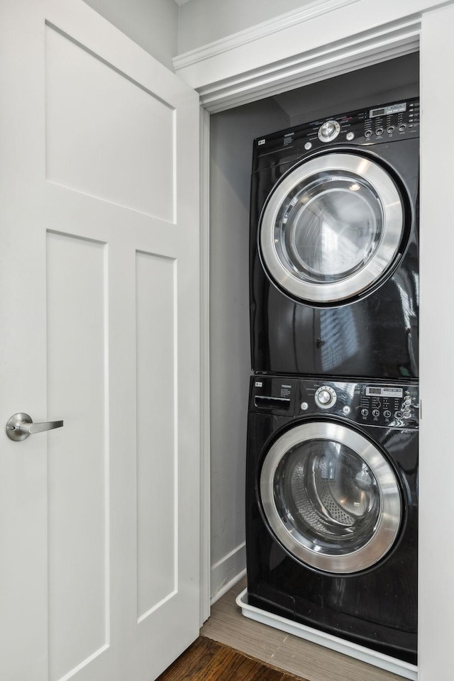 laundry area featuring dark wood-type flooring and stacked washer and clothes dryer