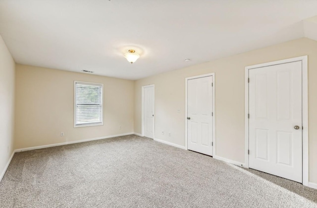 unfurnished bedroom featuring carpet flooring and two closets