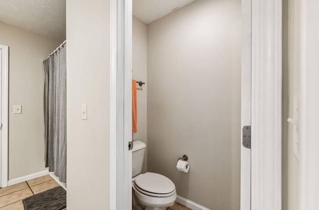 bathroom with tile patterned flooring, a textured ceiling, and toilet