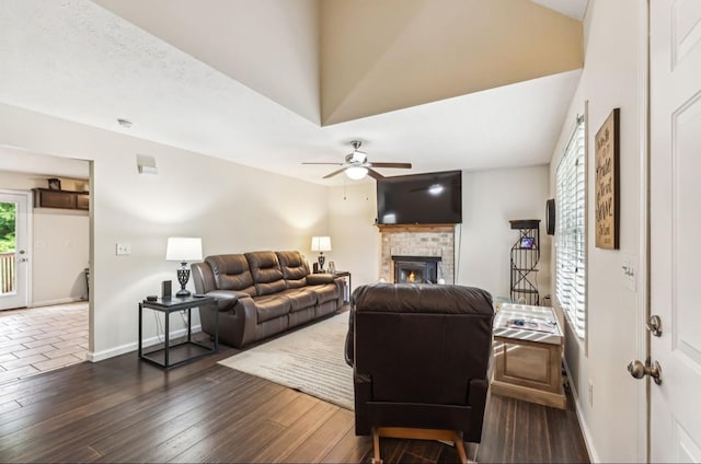 living room with ceiling fan, a fireplace, and dark wood-type flooring