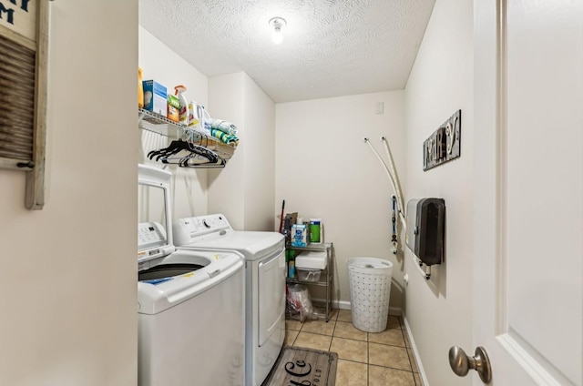 washroom with separate washer and dryer, light tile patterned floors, and a textured ceiling