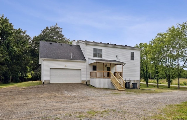 view of front property with covered porch, a garage, and central air condition unit