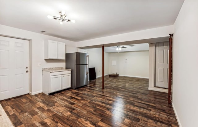 kitchen featuring white cabinets, stainless steel fridge, dark hardwood / wood-style flooring, and ceiling fan with notable chandelier