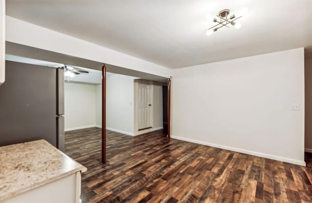 basement with stainless steel fridge, dark hardwood / wood-style flooring, and a notable chandelier