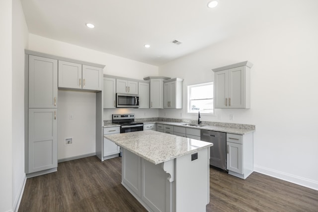 kitchen featuring a center island, dark wood-type flooring, sink, light stone countertops, and appliances with stainless steel finishes