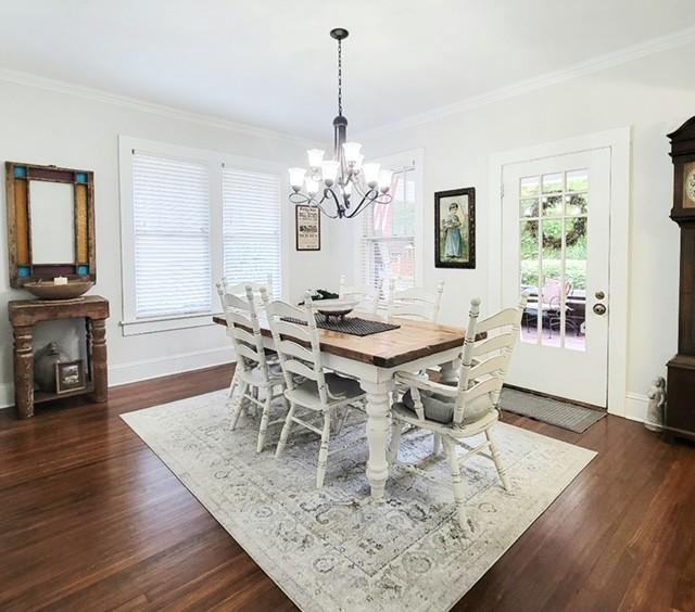 dining space with crown molding, dark wood-type flooring, and a notable chandelier