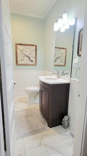 bathroom with vanity, toilet, and crown molding