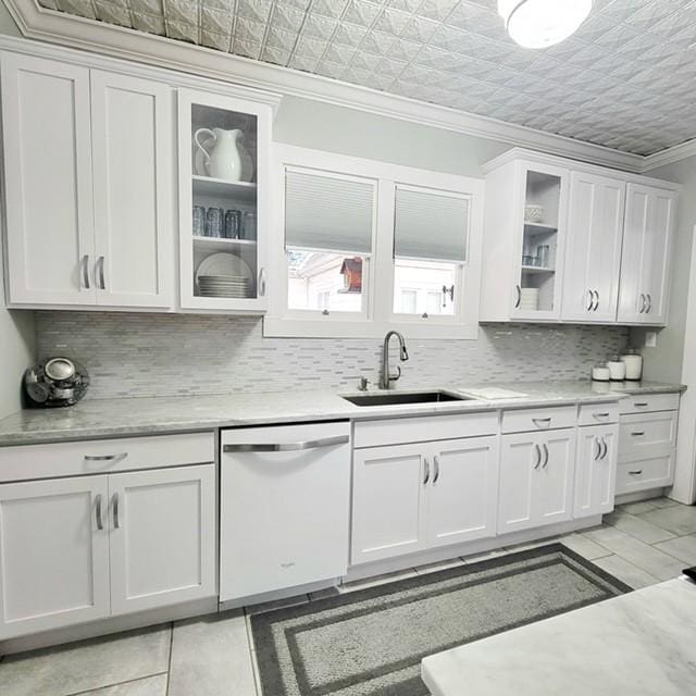 kitchen featuring tasteful backsplash, ornamental molding, white dishwasher, sink, and white cabinetry