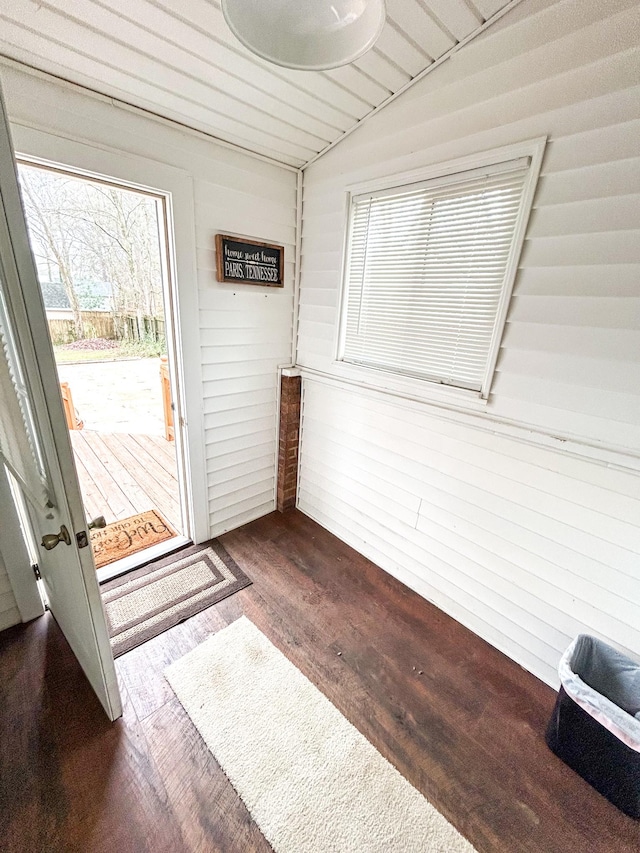 entryway with wooden walls, vaulted ceiling, and dark wood-type flooring