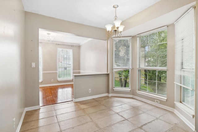 unfurnished dining area with a wealth of natural light, light tile patterned flooring, ornamental molding, and an inviting chandelier