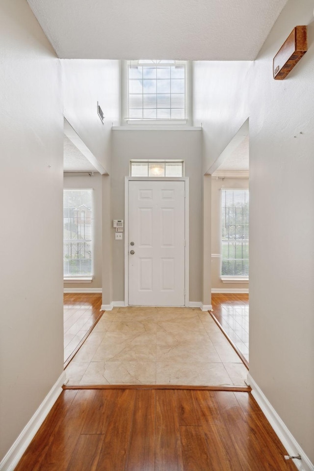 entryway with a wealth of natural light, a high ceiling, and hardwood / wood-style flooring