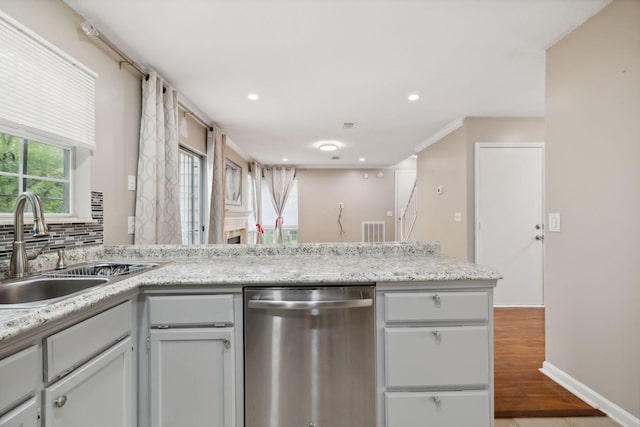 kitchen featuring sink, light hardwood / wood-style flooring, stainless steel dishwasher, decorative backsplash, and light stone countertops