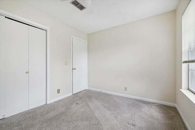 unfurnished bedroom with a closet, light carpet, and multiple windows