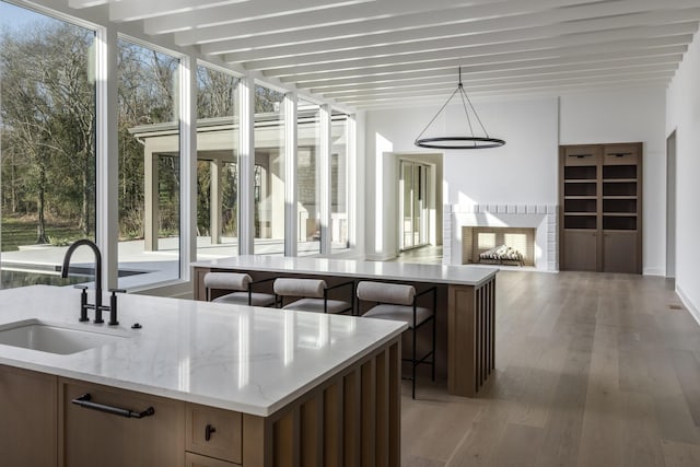 kitchen featuring light stone counters, sink, an island with sink, and pendant lighting