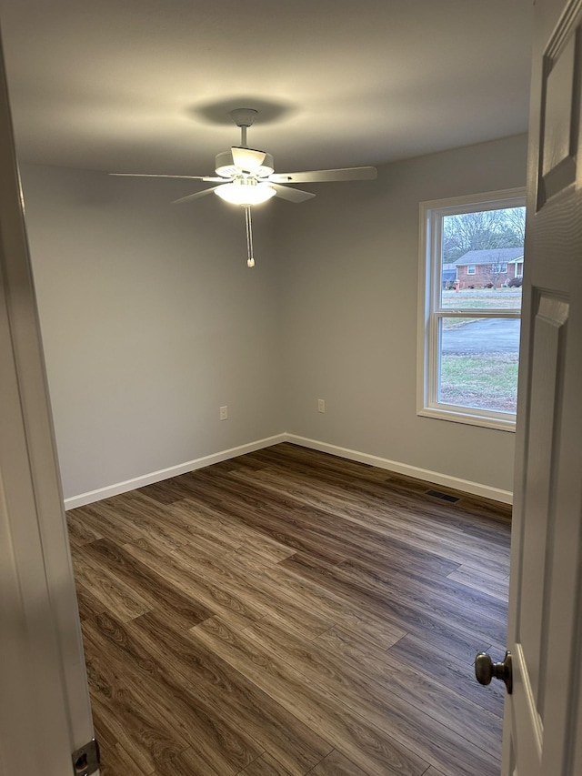 empty room with ceiling fan and dark wood-type flooring