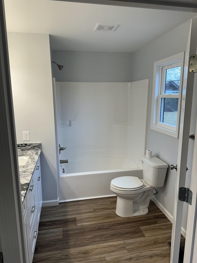 bathroom with shower / bathtub combination, toilet, wood finished floors, vanity, and visible vents