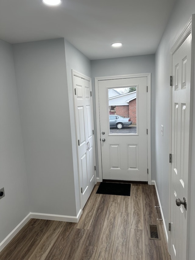 doorway to outside with visible vents, baseboards, and dark wood-style flooring