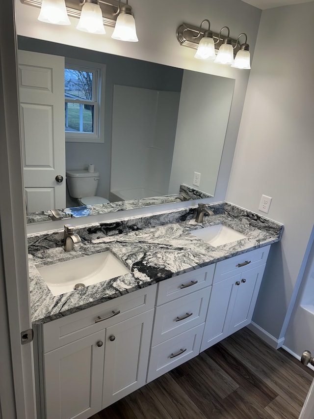 bathroom with toilet, a sink, and wood finished floors