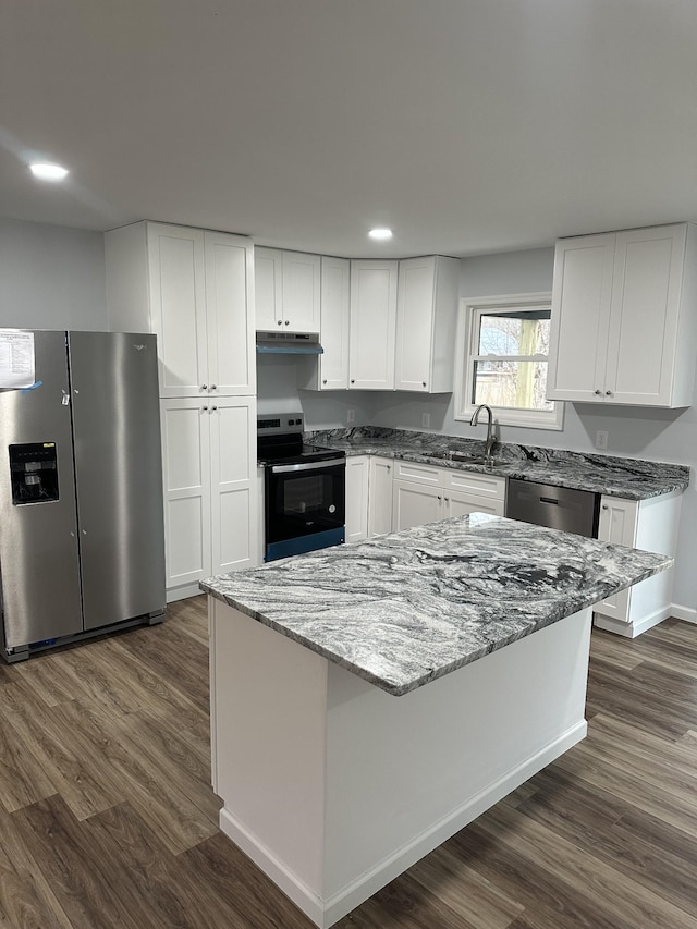 kitchen featuring dark wood-type flooring, a sink, white cabinets, appliances with stainless steel finishes, and light stone countertops