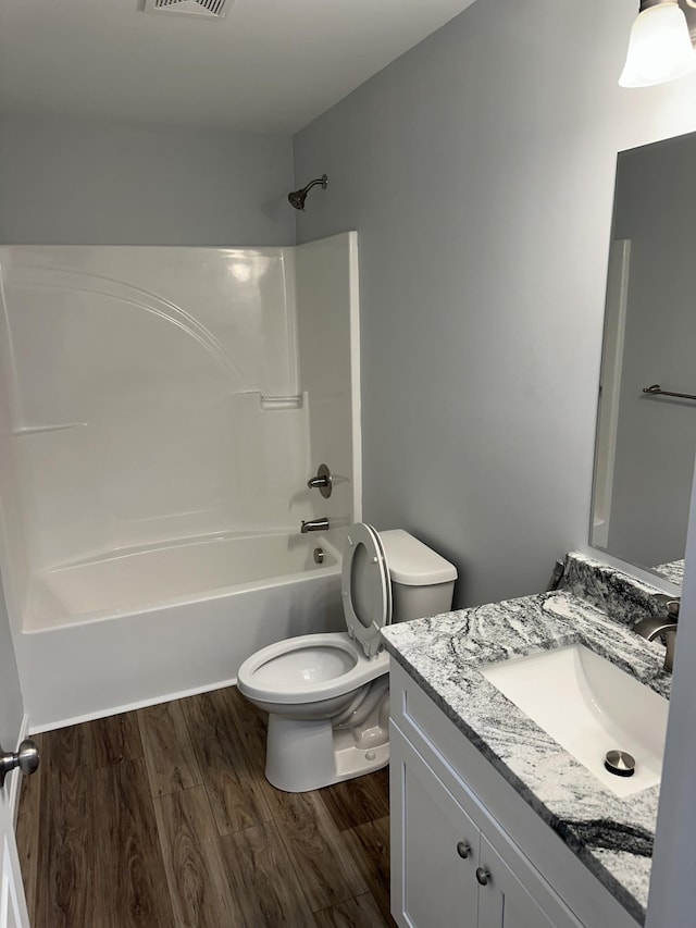 full bath with shower / bath combination, visible vents, toilet, wood finished floors, and vanity