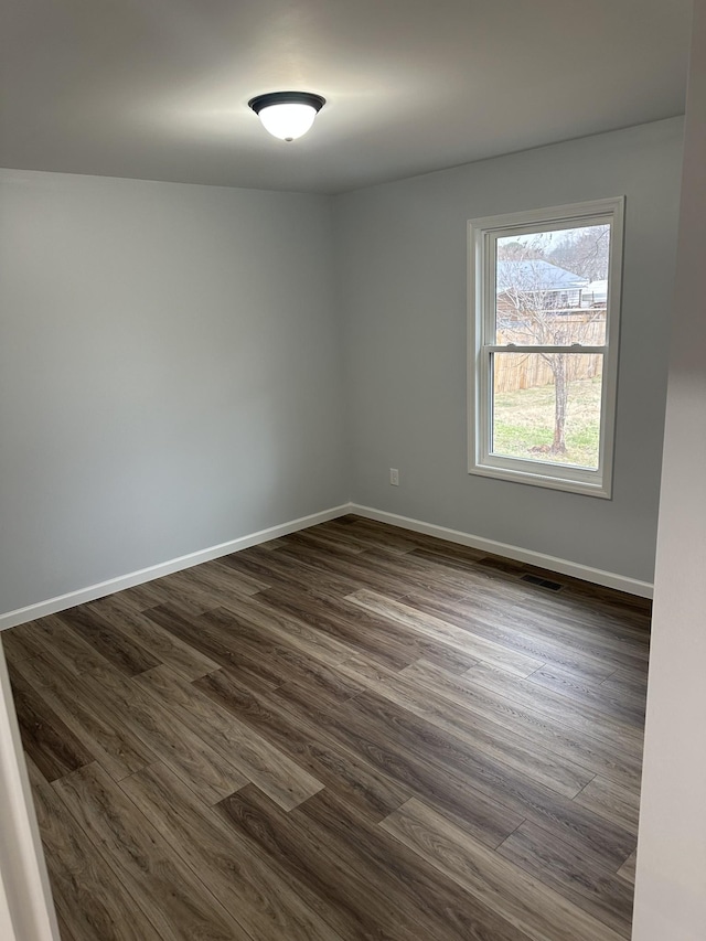 spare room with visible vents, baseboards, and dark wood finished floors