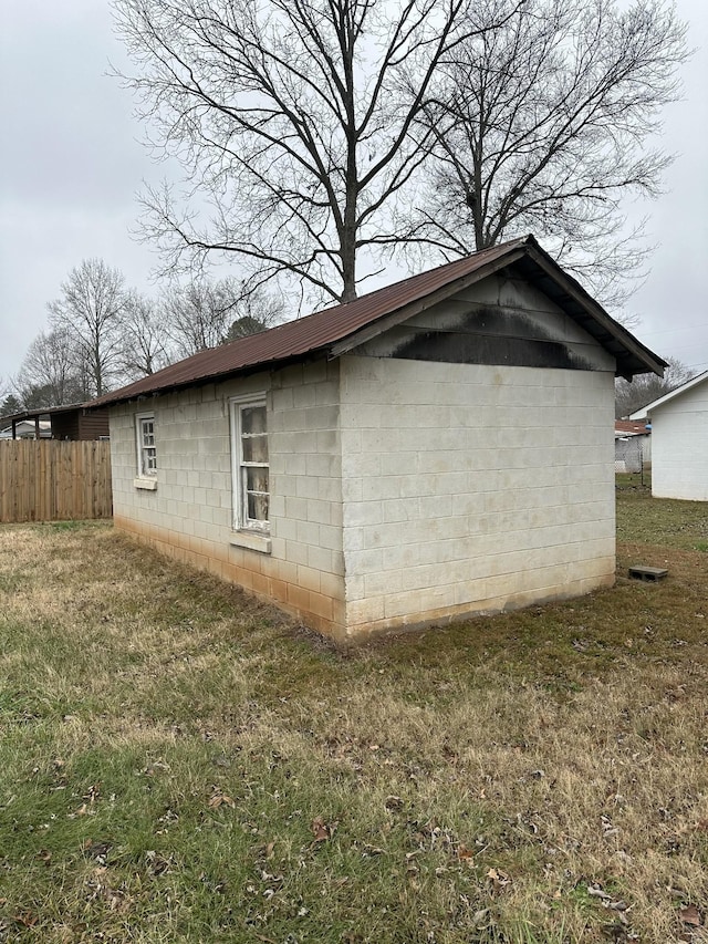 view of property exterior with a yard, concrete block siding, and fence