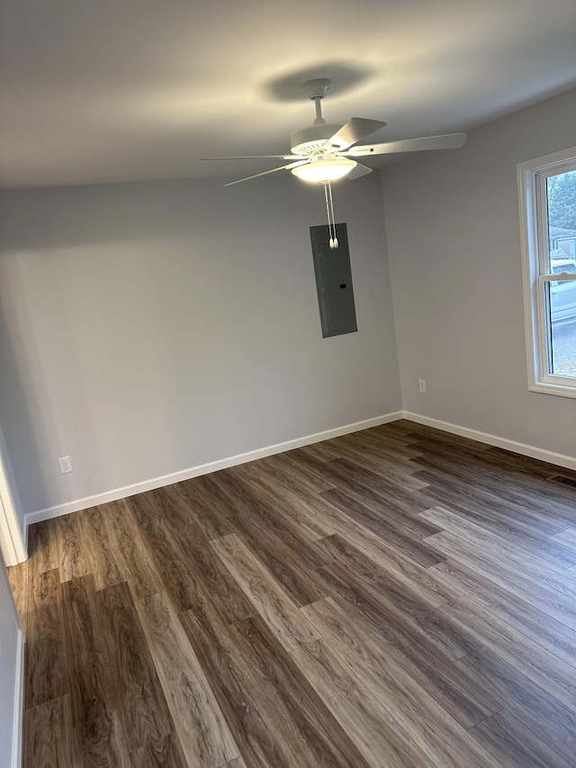 empty room featuring dark wood-type flooring, electric panel, ceiling fan, and baseboards