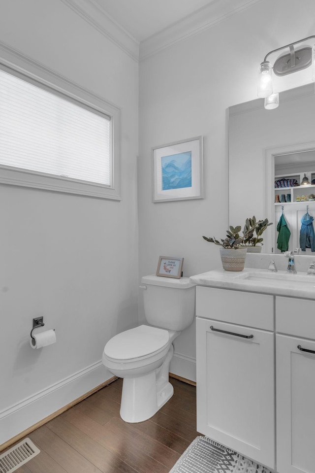 bathroom with built in shelves, crown molding, wood-type flooring, toilet, and vanity