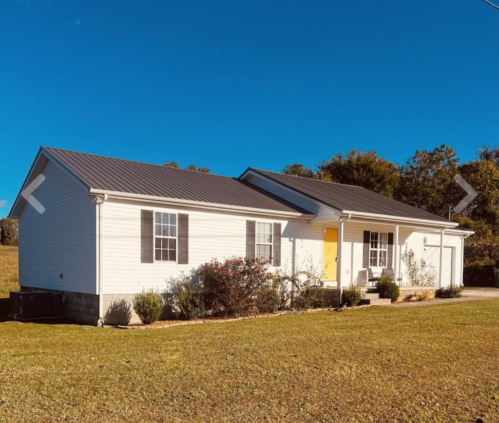 ranch-style home featuring a garage, a front lawn, and cooling unit