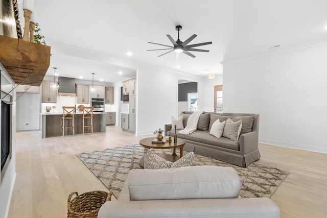 living room featuring crown molding, light hardwood / wood-style flooring, and ceiling fan