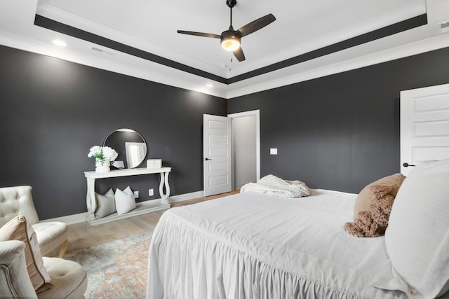 bedroom featuring a raised ceiling, ceiling fan, and light hardwood / wood-style floors