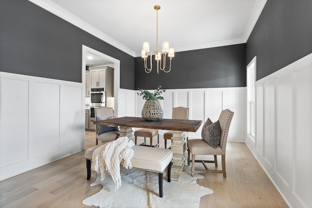 dining area with ornamental molding, light hardwood / wood-style floors, and a chandelier