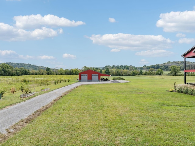 view of yard featuring an outbuilding, a rural view, and a garage