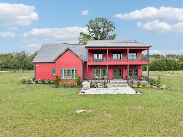 rear view of property featuring a lawn, a balcony, a patio, and french doors