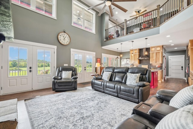 living room featuring ceiling fan, french doors, a towering ceiling, and wood-type flooring