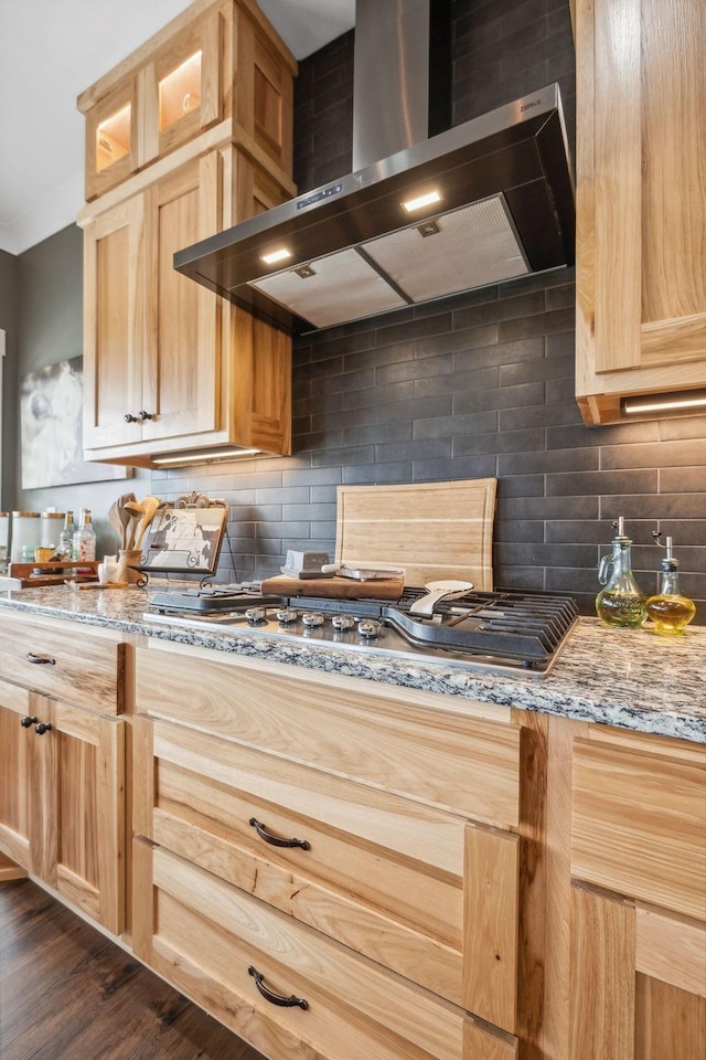 kitchen with decorative backsplash, light stone counters, wall chimney range hood, light brown cabinets, and dark hardwood / wood-style floors