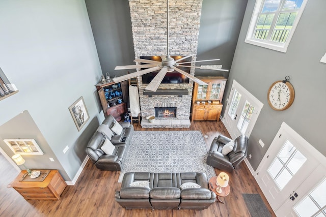 living room featuring ceiling fan, a healthy amount of sunlight, a towering ceiling, and a fireplace