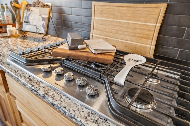 room details with decorative backsplash, light brown cabinetry, and stainless steel gas stovetop