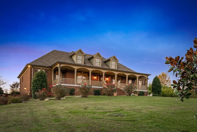 view of front of home with covered porch and a yard