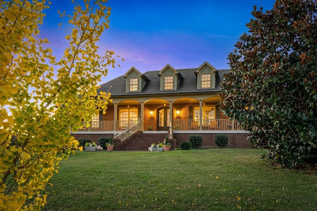 cape cod-style house with a lawn and covered porch