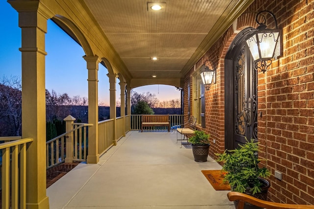 patio terrace at dusk featuring covered porch