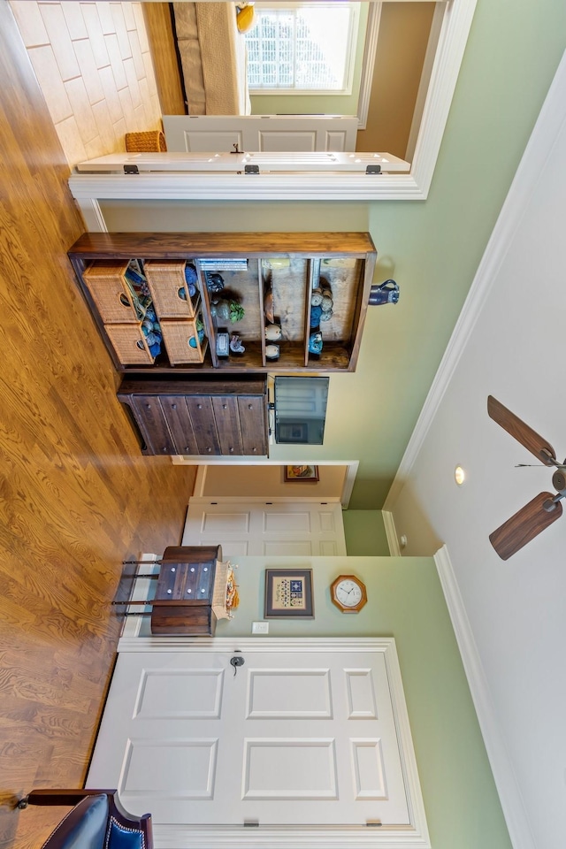 interior space featuring ornamental molding, a towering ceiling, ceiling fan, and wooden walls