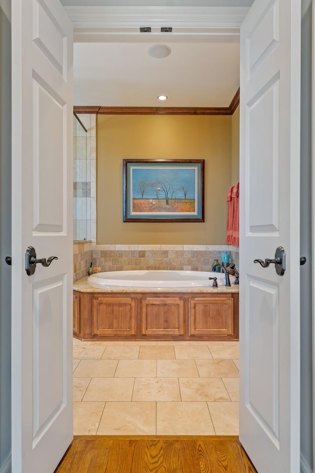 bathroom featuring tile patterned flooring, crown molding, and a tub to relax in