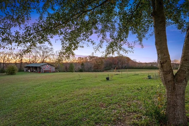 yard at dusk featuring a rural view and an outdoor structure