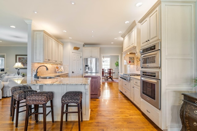 kitchen with kitchen peninsula, appliances with stainless steel finishes, a breakfast bar, and sink