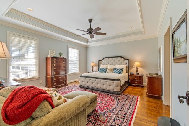 bedroom with a raised ceiling, ceiling fan, hardwood / wood-style floors, and crown molding