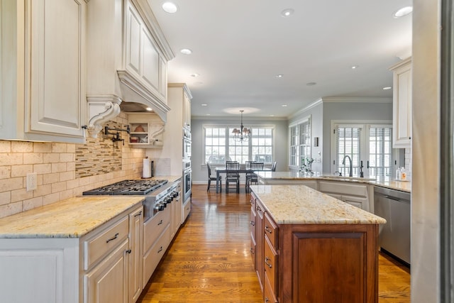 kitchen featuring light stone countertops, tasteful backsplash, stainless steel appliances, sink, and decorative light fixtures