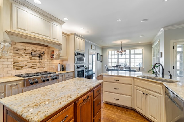 kitchen with pendant lighting, sink, light wood-type flooring, appliances with stainless steel finishes, and a chandelier